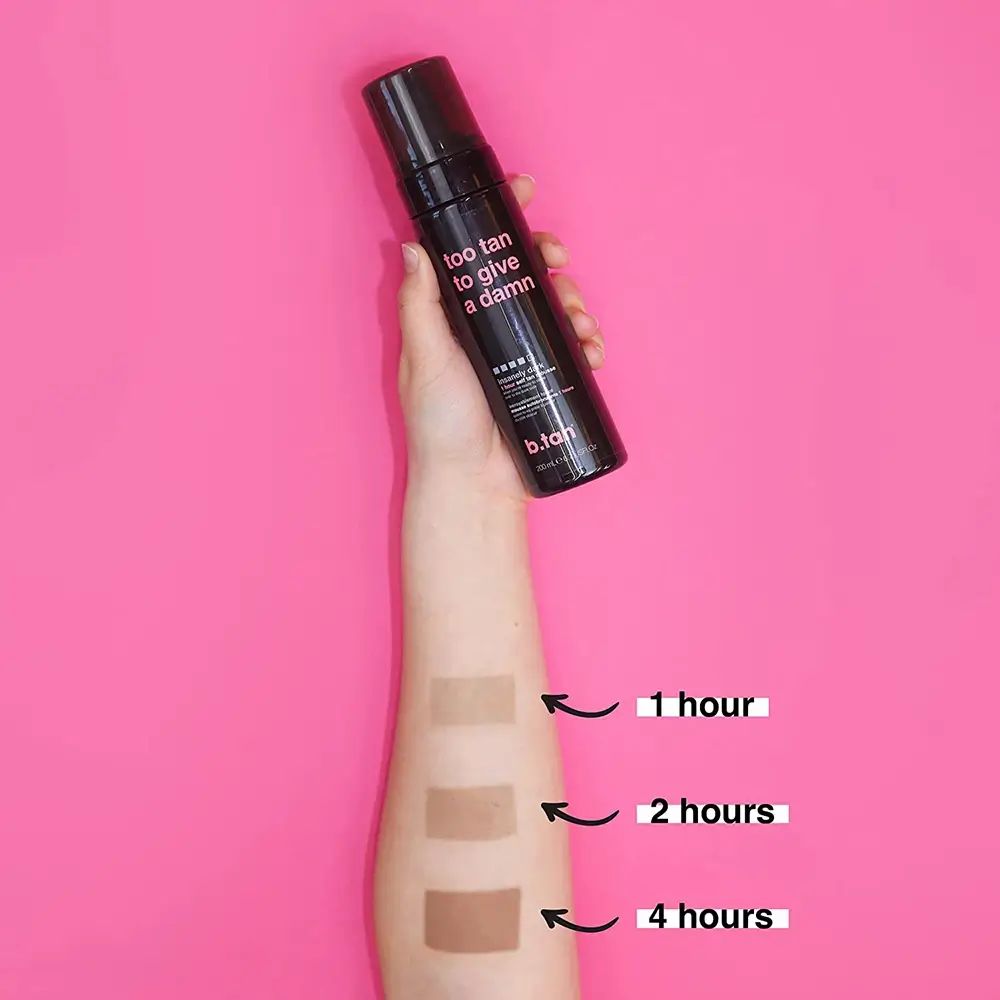 Arm mit drei Bräunungstests. Schwarze Flasche mit Aufschrift "too tan to give a damn" wird gehalten. Pinker Hintergrund.