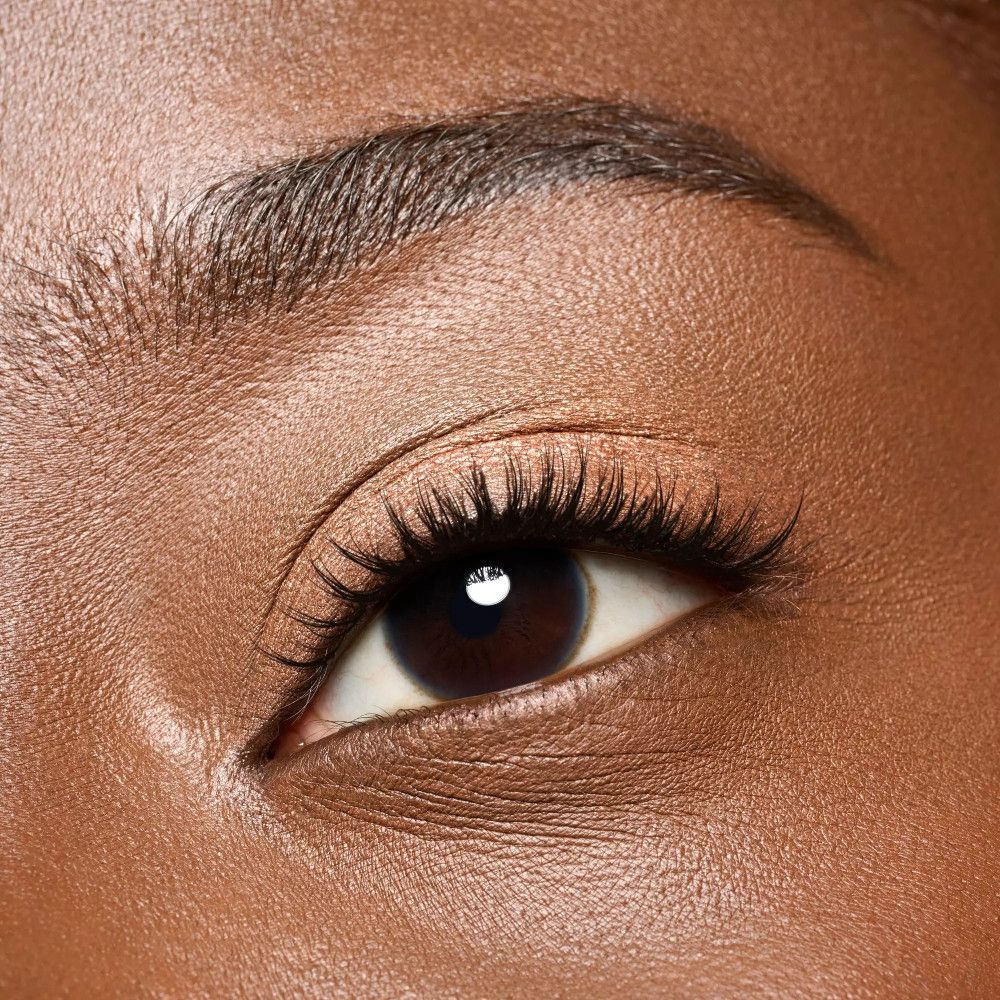 Nahaufnahme eines Auges. Dunkle Haut, dunkle Augenbraue, lange Wimpern. Augenlid mit Lidschatten.