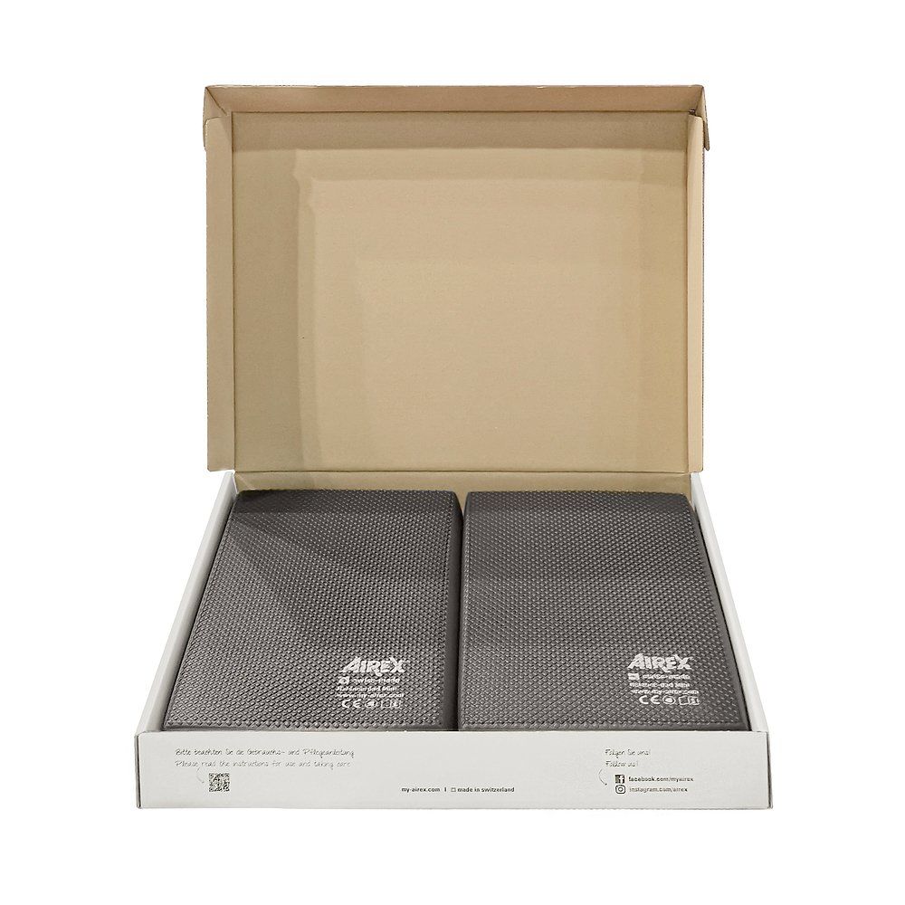 Zwei graue Balance-Pads in einer geöffneten Pappschachtel. Auf jedem Pad ist das Airex-Logo und CE-Kennzeichnung zu sehen.
