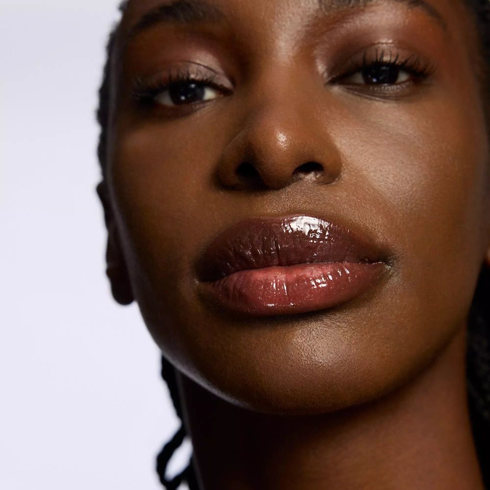 Nahaufnahme einer Frau mit glänzenden, dunklen Lippen. Sie trägt dunklen Lippenstift und Glanz.