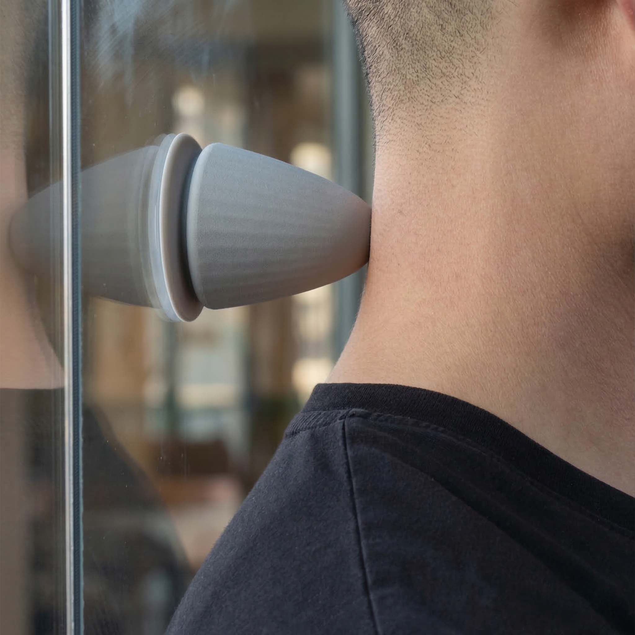 Graues, kegelförmiges Produkt wird am Hals einer Person verwendet. Reflektion auf Glas.