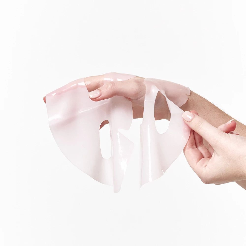 Hände halten eine rosa Hydrogel-Maske. Die Maske ist transparent und hat eine Gesichtsform.