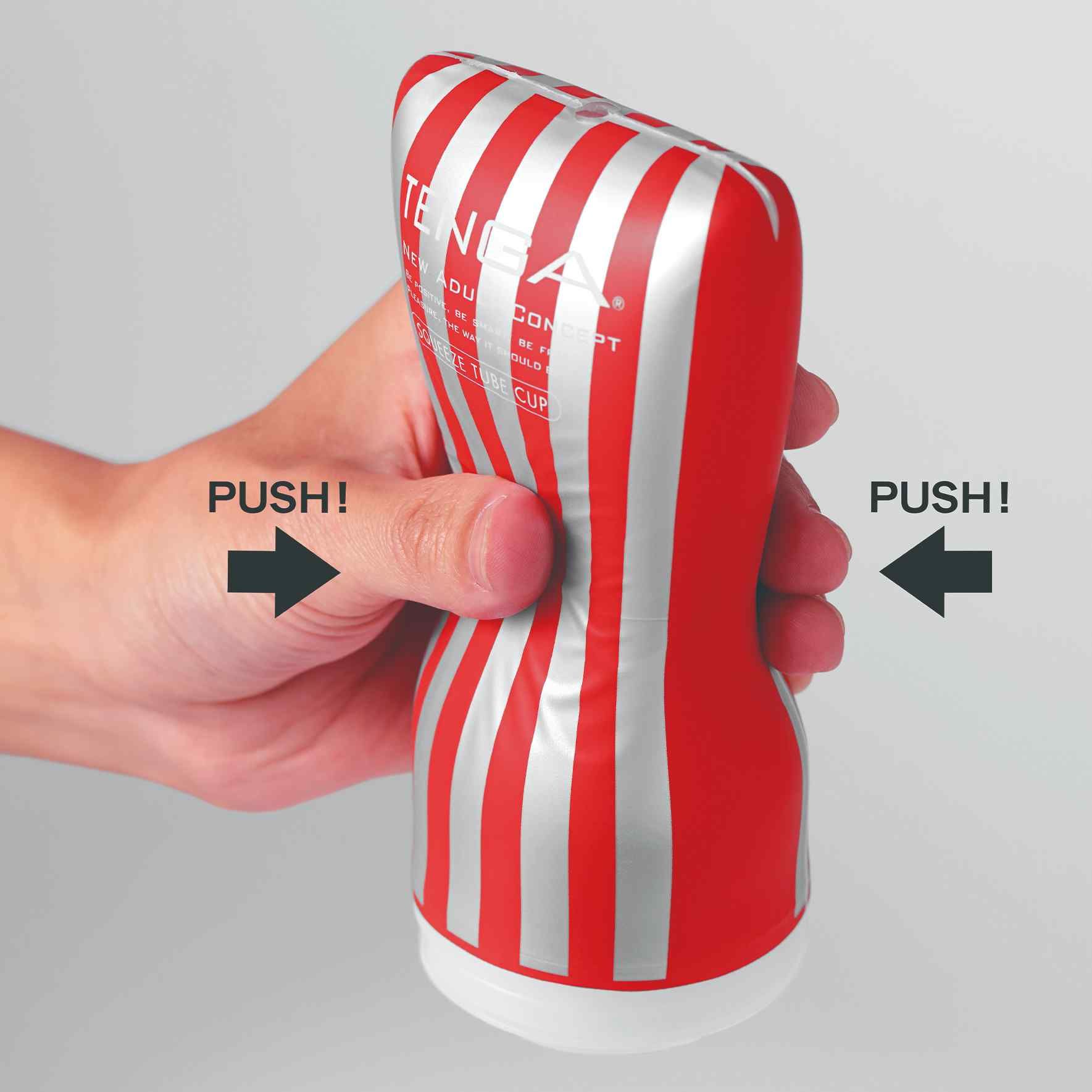 Roter und silberner Tube Cup. Das Produkt wird von einer Hand zusammengedrückt. Pfeile mit "PUSH!" weisen auf die Seiten.