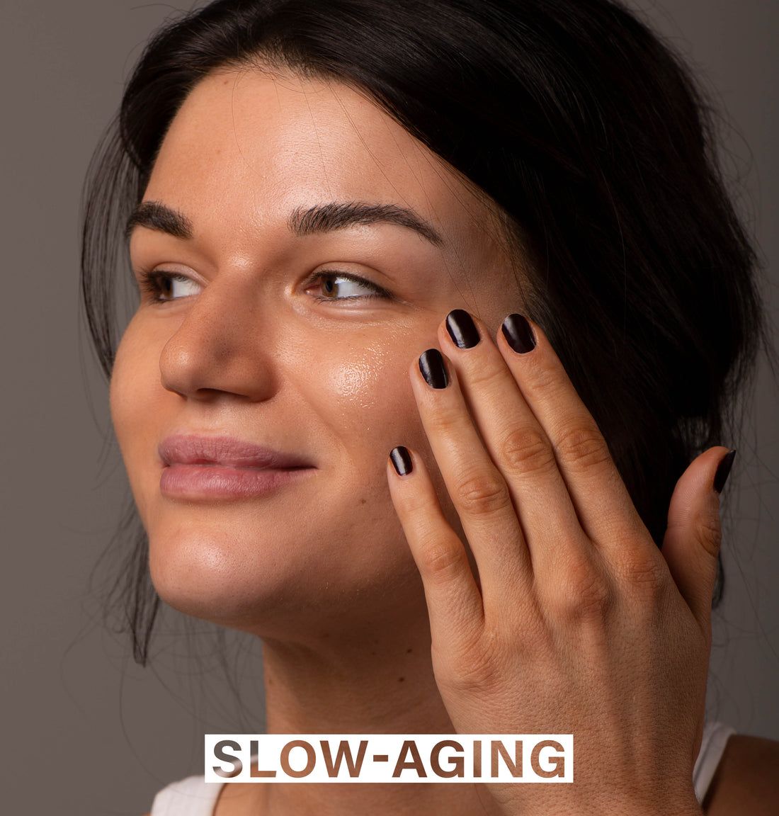 Frau berührt ihr Gesicht. Aufschrift: SLOW-AGING.