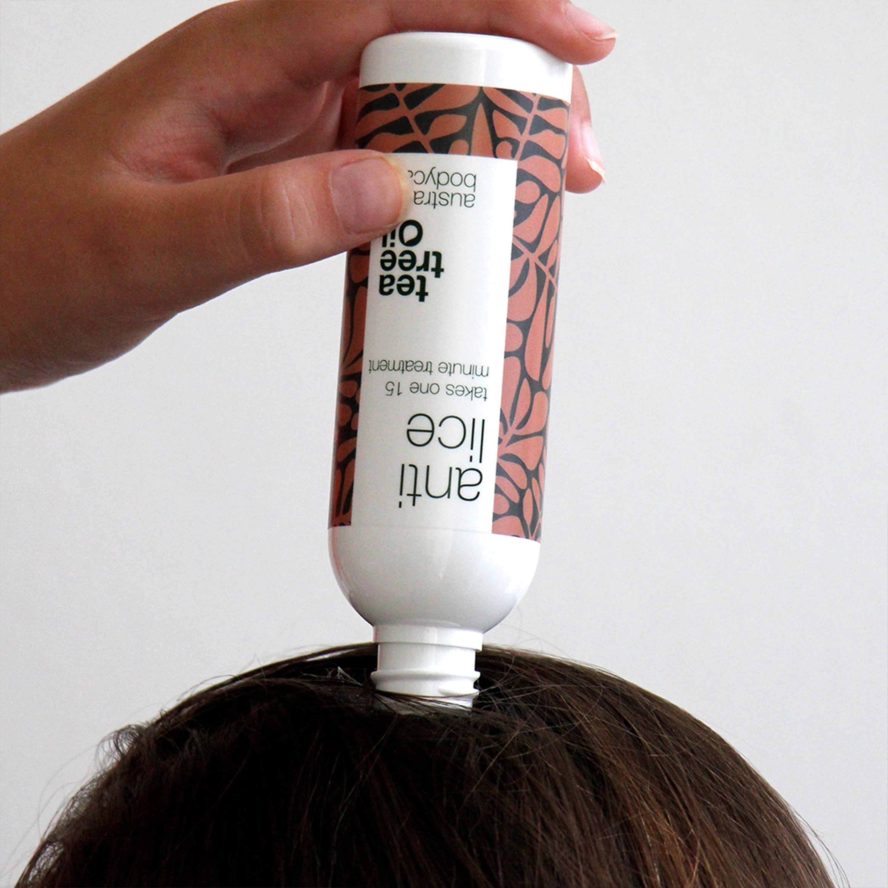 Flasche mit „Anti Lice“-Aufdruck wird auf Kopf gehalten. Braunes Muster. „Tea Tree Oil“ Aufdruck. Weißer Deckel.