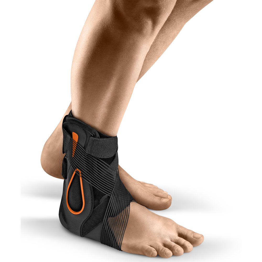 Schwarze und orangefarbene Sprunggelenkorthese. Elastische Bänder und Klettverschlüsse. Am Bein einer Person getragen.
