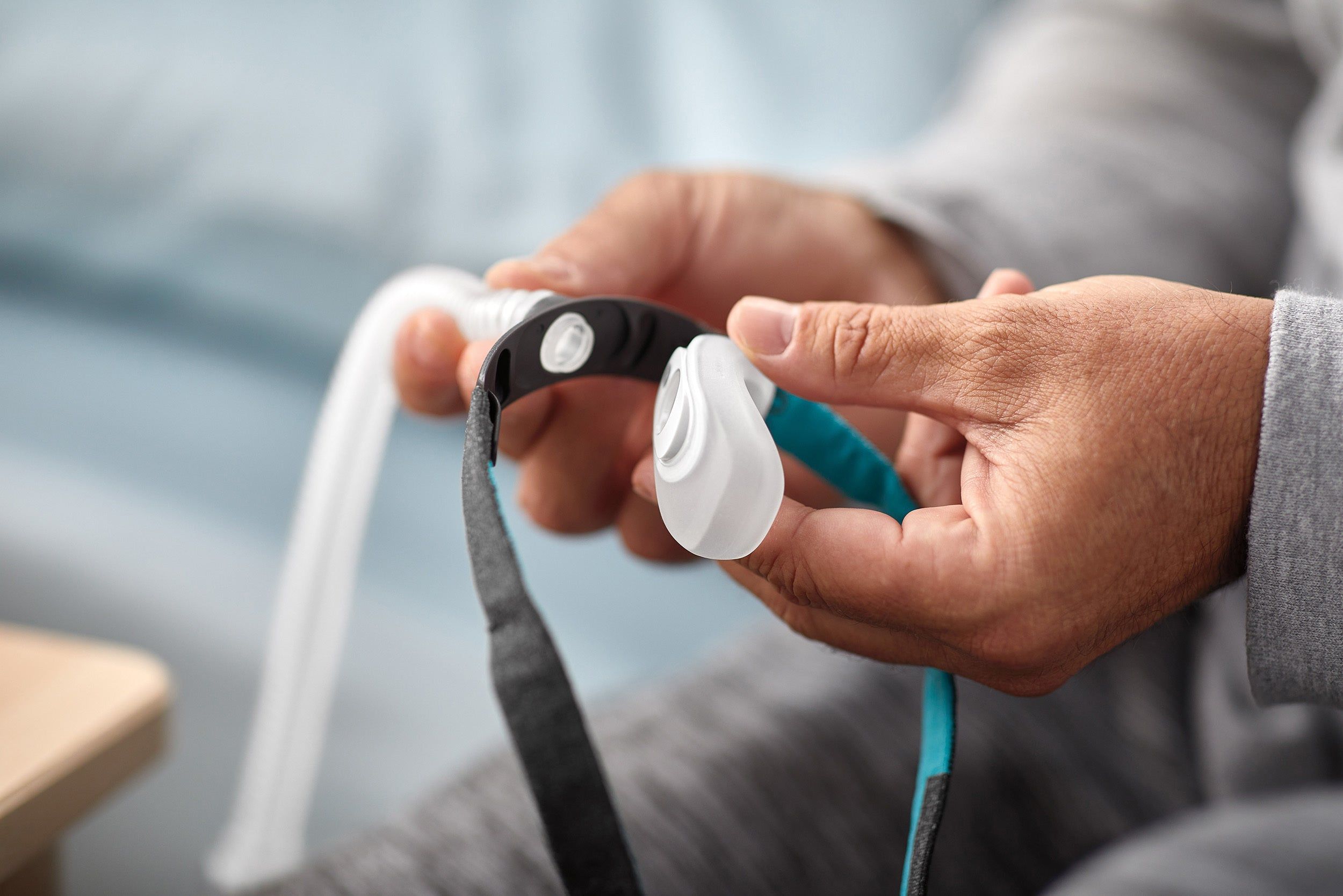 Hände halten CPAP-Nasenmaske mit Schlauch und Kopfteil.