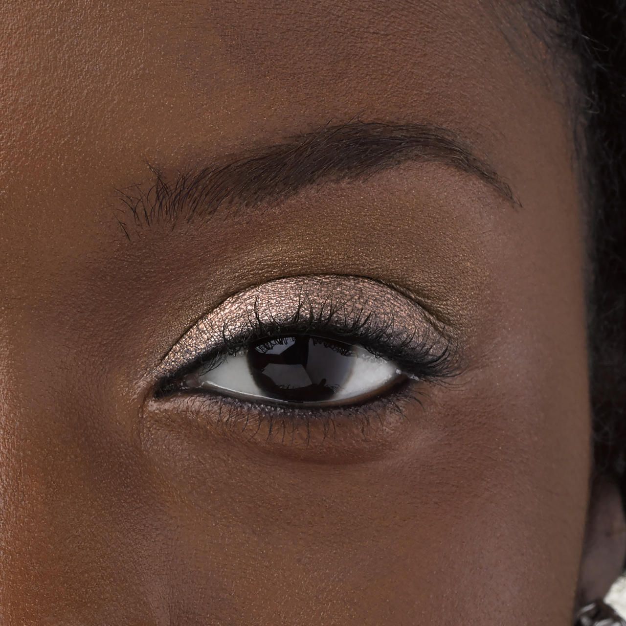 Auge mit braunem Eyeshadow geschminkt. Wimpern getuscht.