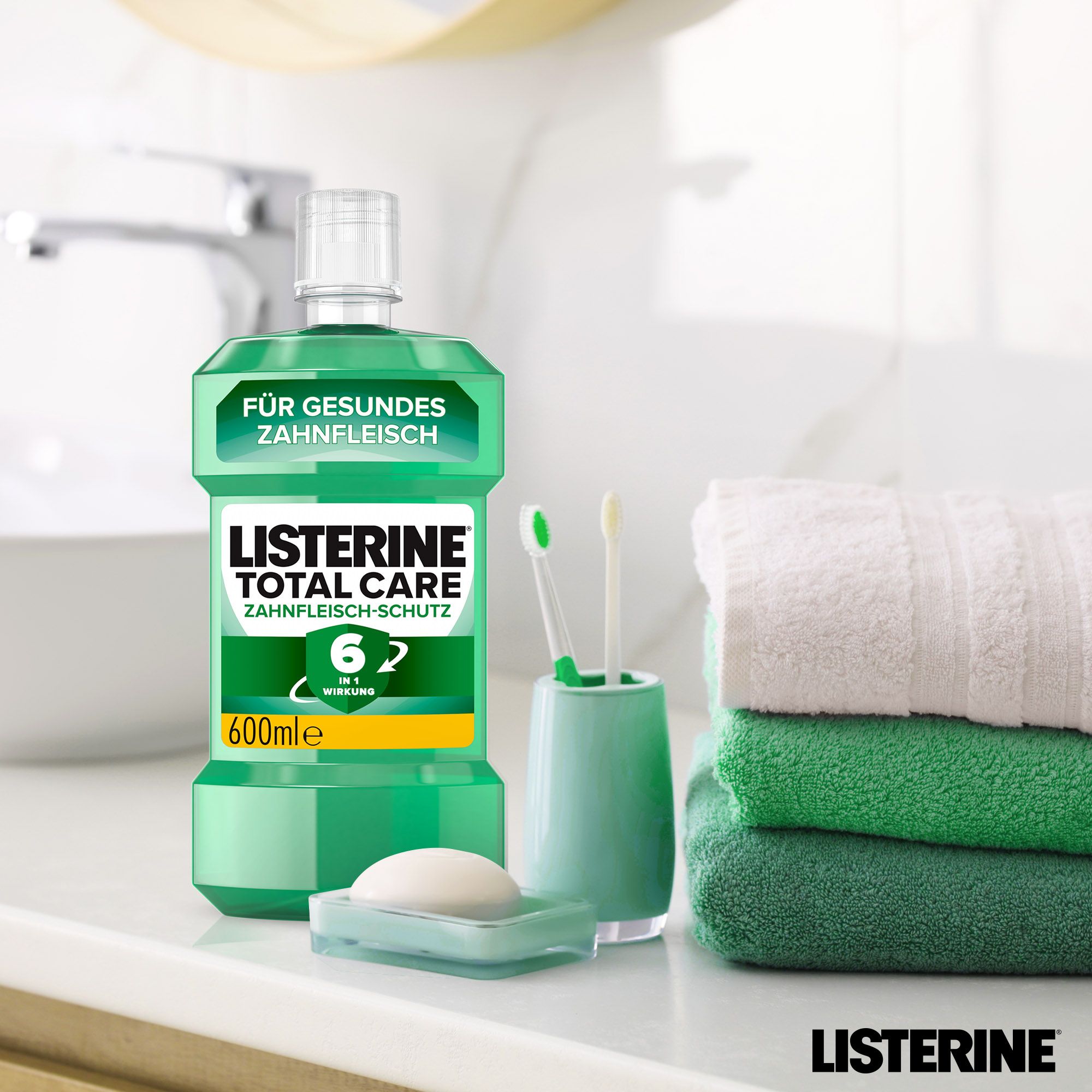 Listerine Total Care Zahnfleisch-Schutz Flasche, 600ml, neben Zahnbürsten, Seife und Handtüchern.