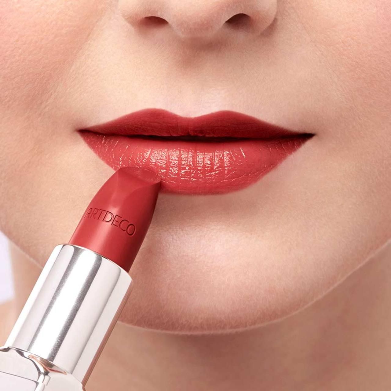 Person trägt roten Lippenstift auf den Lippen auf. Auf dem Lippenstift steht "ARTDECO".