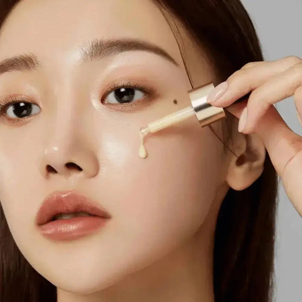 Gesicht einer Frau mit Hautpflege. Ein Tropfen Serum wird mit einer Pipette aufgetragen. Goldfarbene Pipette.