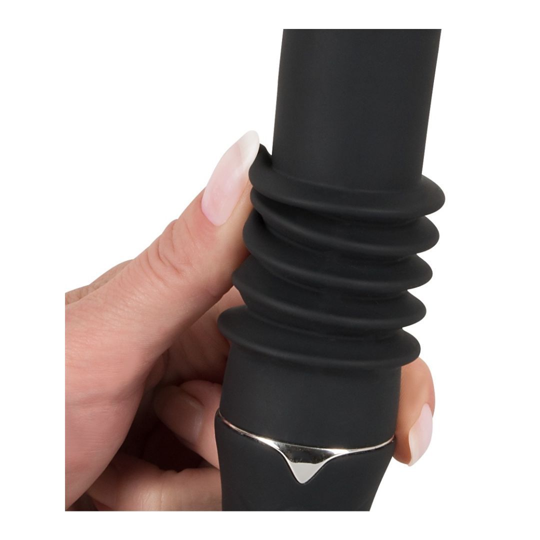 Nahaufnahme eines schwarzen Vibrators. Geriffelte Mitte, silberfarbener Akzent. Hand berührt das Produkt.
