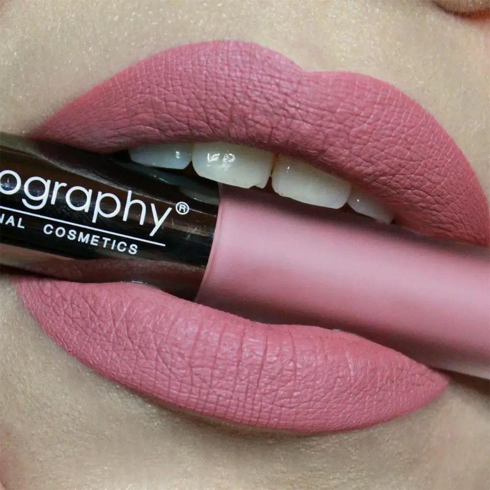 Mund mit Lippenstift. Lippen mit rosa Lippenstift bemalt. Lippenstift-Tube im Mund.