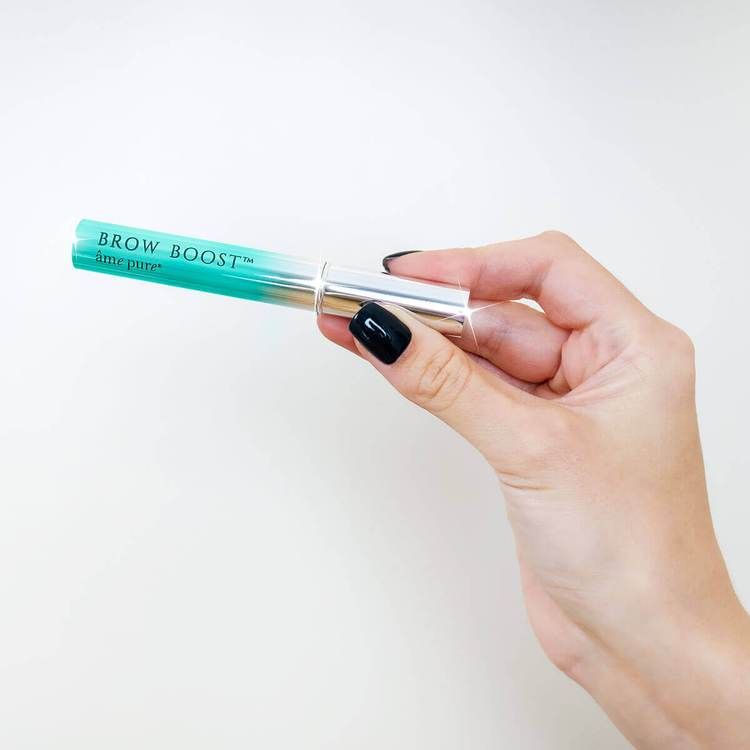 Person hält Augenbrauenserum. Aufschrift: BROW BOOST, âme pure. Flasche mit Applikator, silberner Kappe und blauem Deckel.