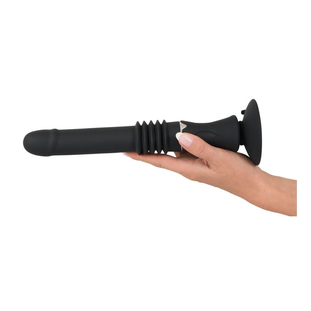 Schwarzer Vibrator, gehalten von einer Hand. Abgerundete Spitze, geriffelte Mitte, Saugfuß.