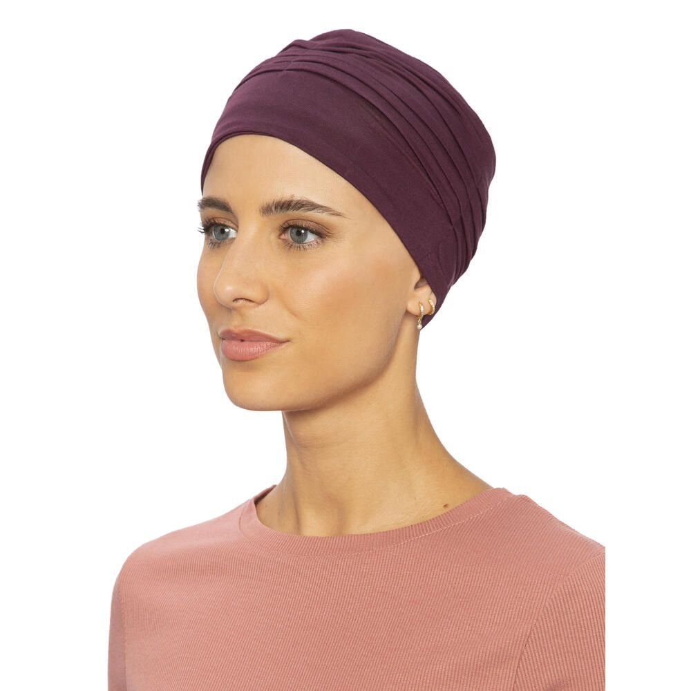 Burgunderfarbener Turban. Seitenansicht einer Frau, die ihn trägt. Gerüschte Textur. Angenehmes Material. Auf hellem Hintergrund.