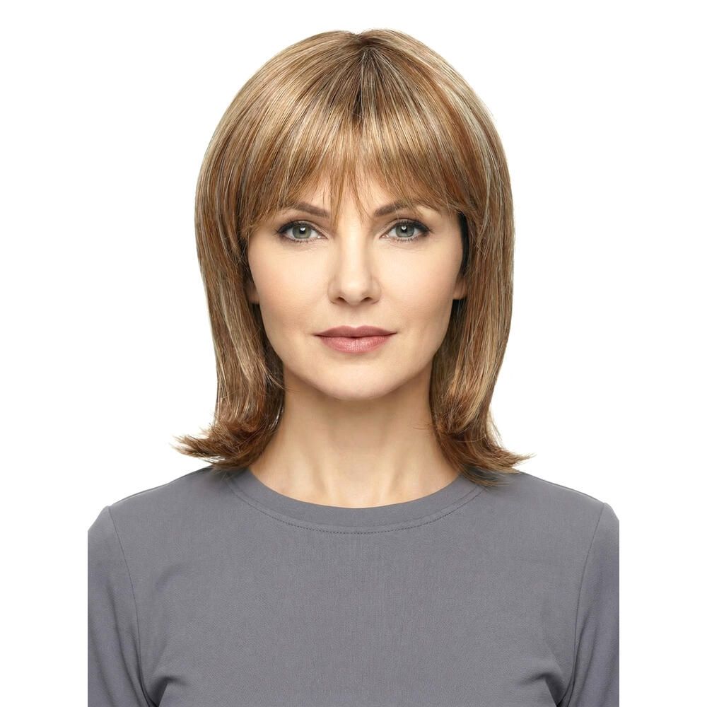 Perücke Mola von trendhair. Blond-braune Haarfarbe mit Pony. Mittellange, gestufte Frisur. Frau trägt graues Oberteil.