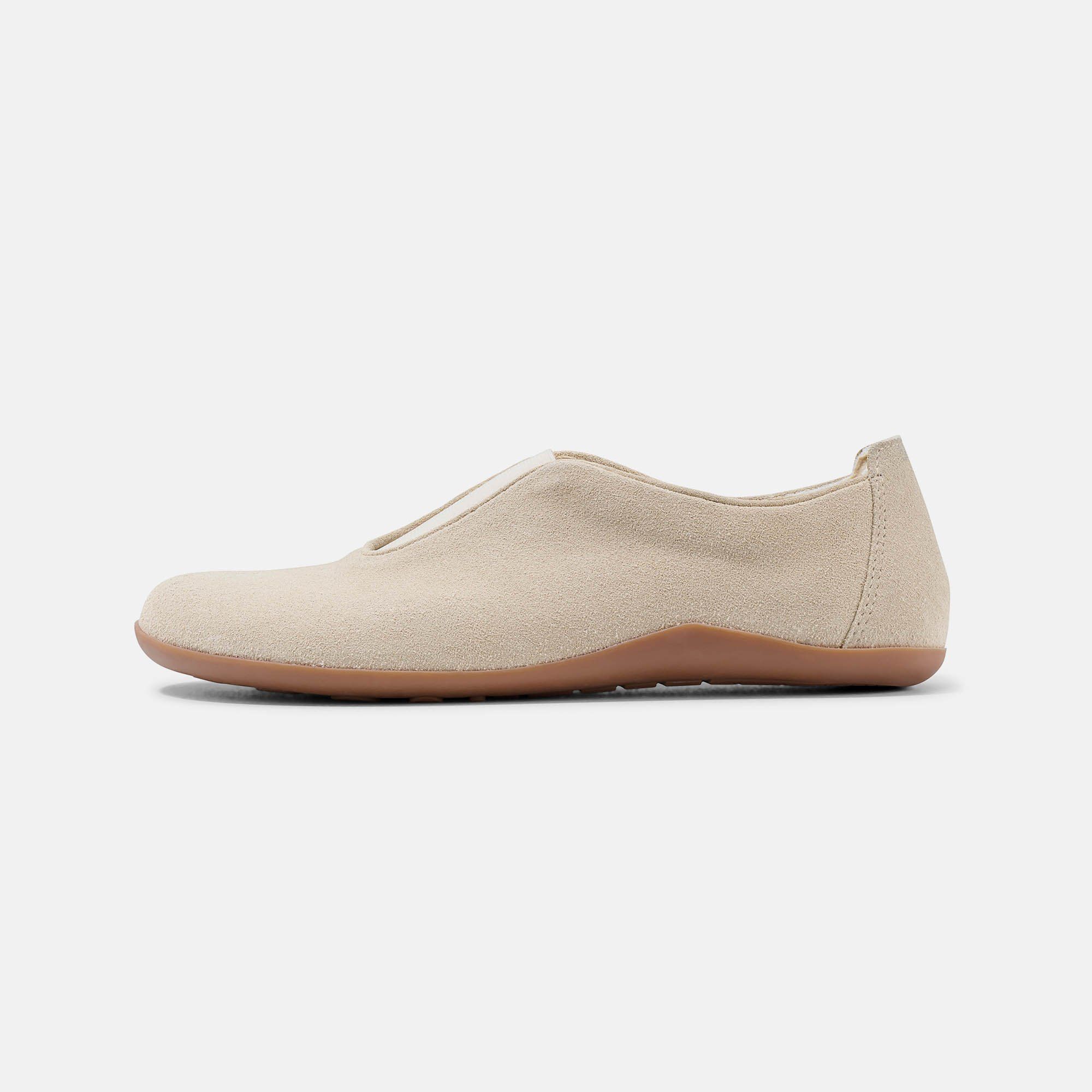 Beigefarbener Slipper. Obermaterial aus Wildleder, helle Zunge, braune Sohle. Seitenansicht.