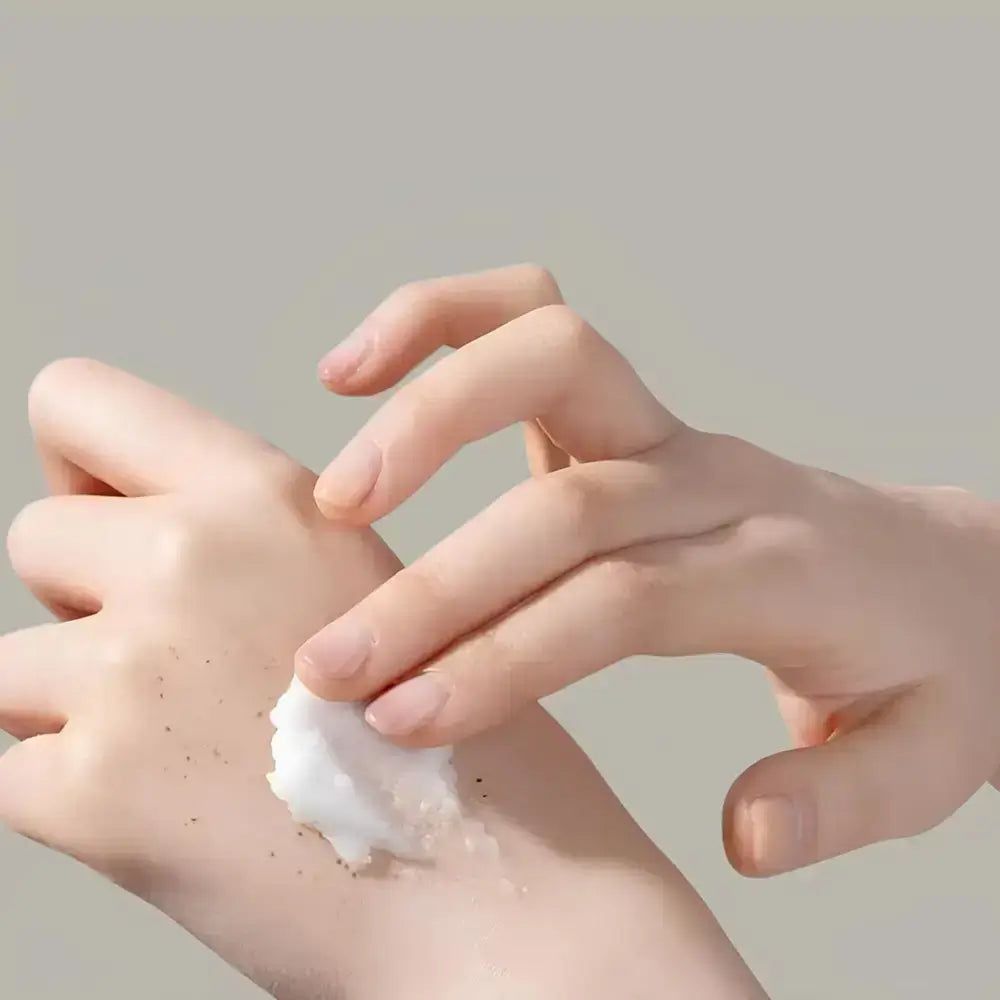 Hände mit weißem Peeling und feinen Partikeln.