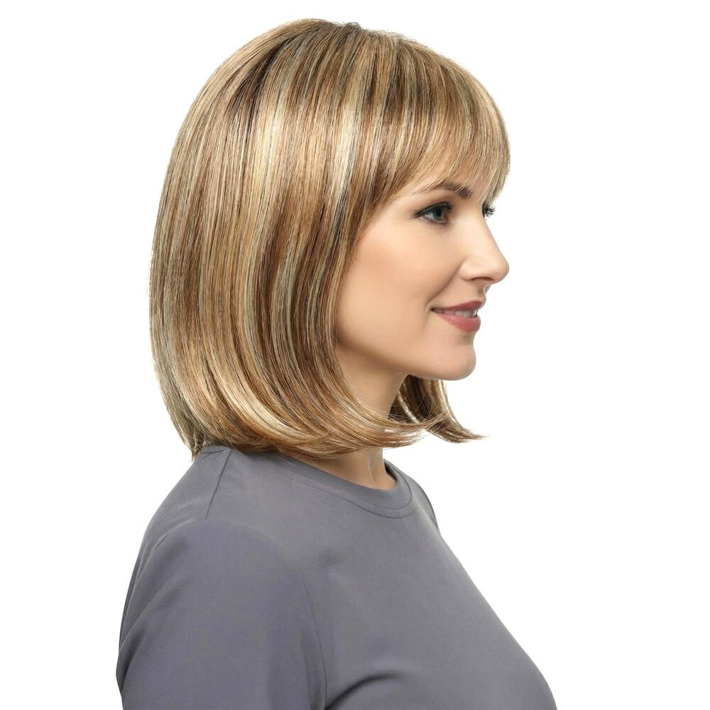Perücke Mola von trendhair. Blond-braune Haarfarbe mit Pony. Mittellange, gestufte Frisur. Frau trägt graues Oberteil.