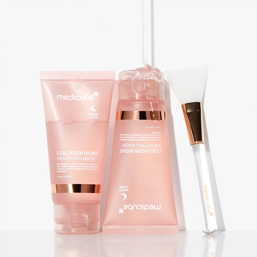Zwei rosa Tuben und ein Applikatorpinsel liegen nebeneinander. Eine Tube enthält eine klare Gelmaske.