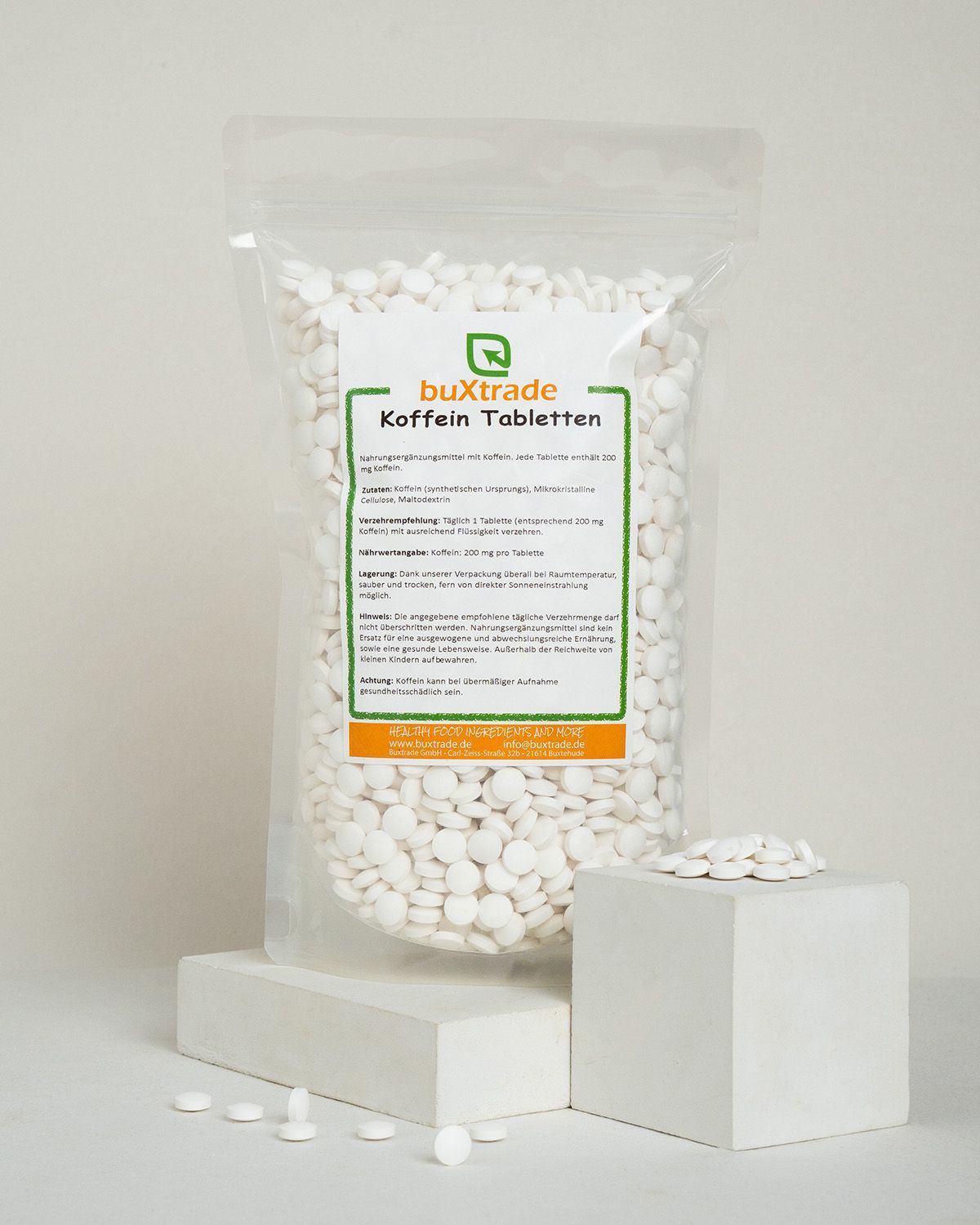 Verpackung mit buxtrade Koffein Tabletten und einige Tabletten daneben.