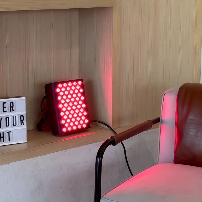 Rotes Lichtgerät auf Regal. Rechteckige Form, viele runde Öffnungen. Schwarzes Gehäuse.