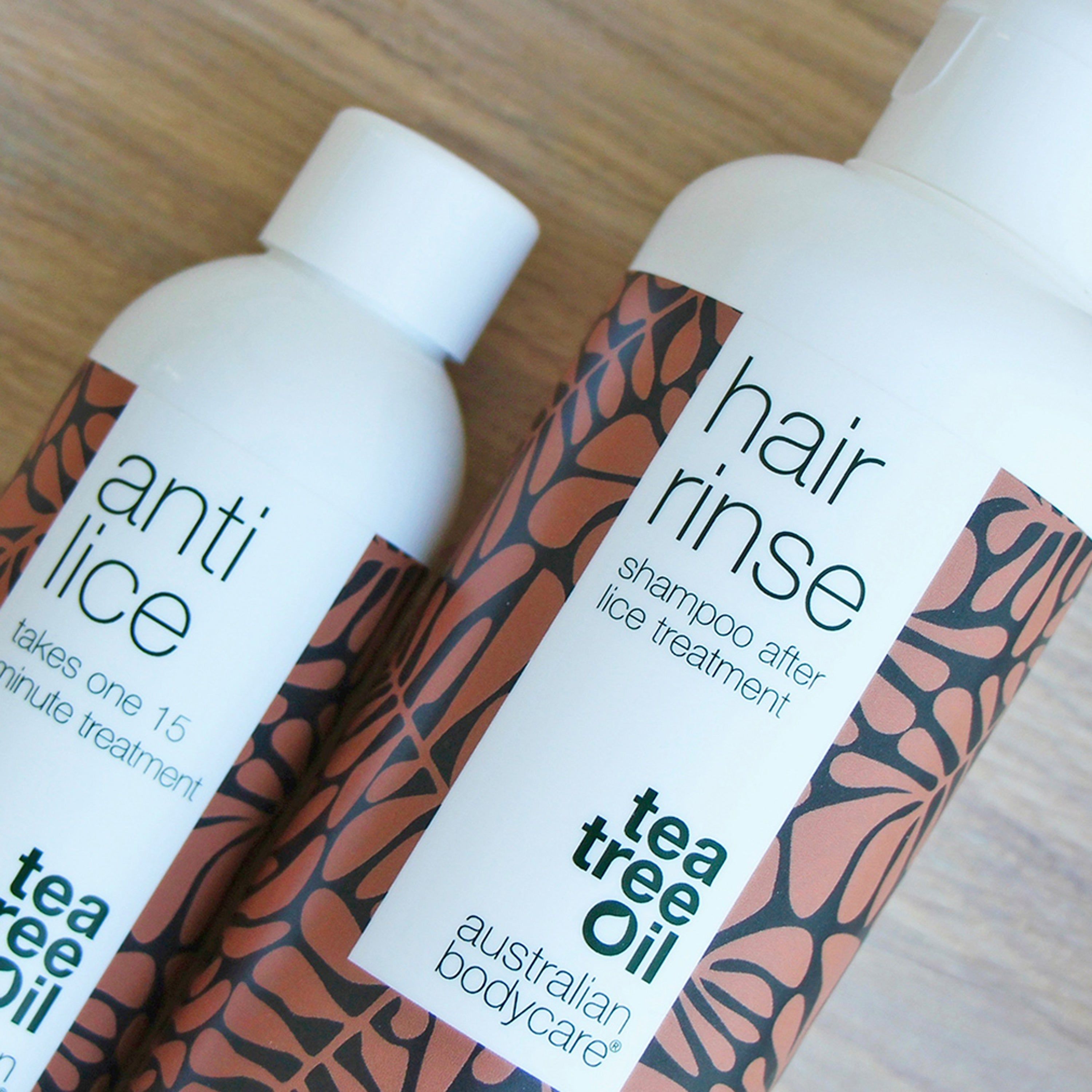 Zwei Flaschen mit braunem Blattmuster. Aufschrift: anti lice, hair rinse, Tea Tree Oil, australian bodycare.