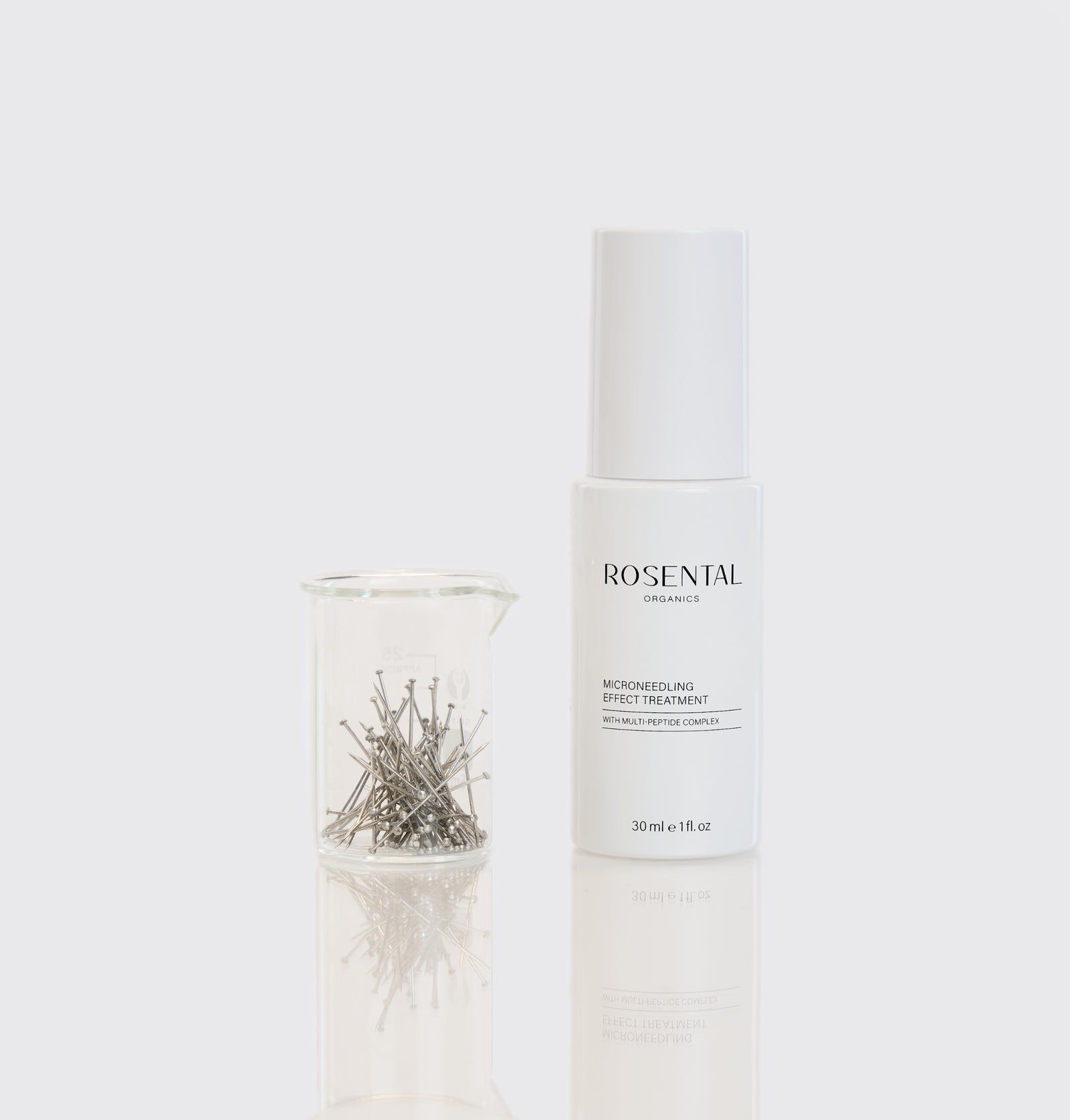 Weiße Flasche mit ROSENTAL Organics und ein Becherglas mit Metallnadeln. Produkt: Microneedling Effect Treatment.