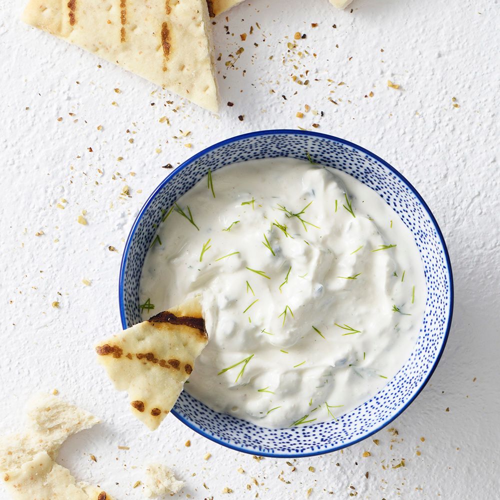 Blaue Schüssel mit Tzatziki und Fladenbrot. Draufsicht. Weißer Hintergrund.