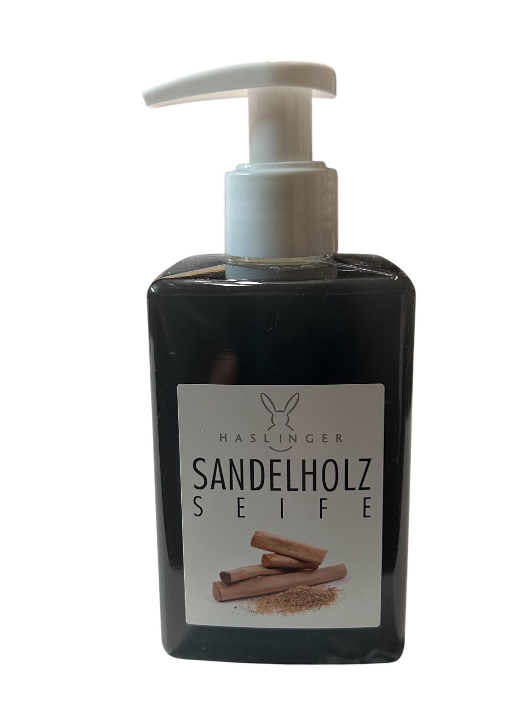 Schwarze Flüssigseife mit weißem Spender. Aufkleber mit Text: SANDELHOLZ SEIFE, Haslinger Logo. Abbildung von Sandelholz.