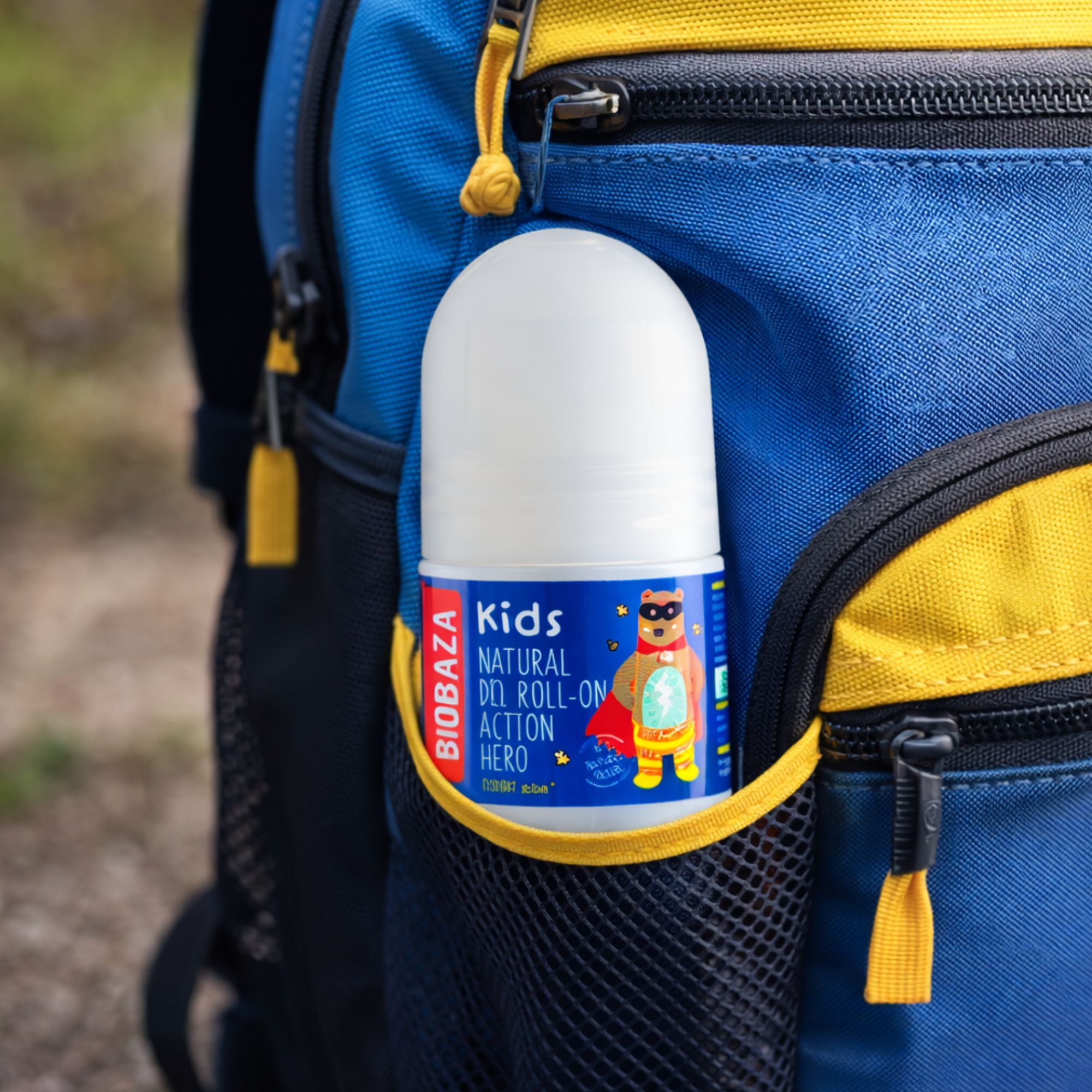 Deo-Rollon für Kinder in Rucksacktasche. Weißer Behälter mit blauem Etikett. Aufschrift: Kids, Natural Deo Roll-on Action Hero. Rucksack blau.