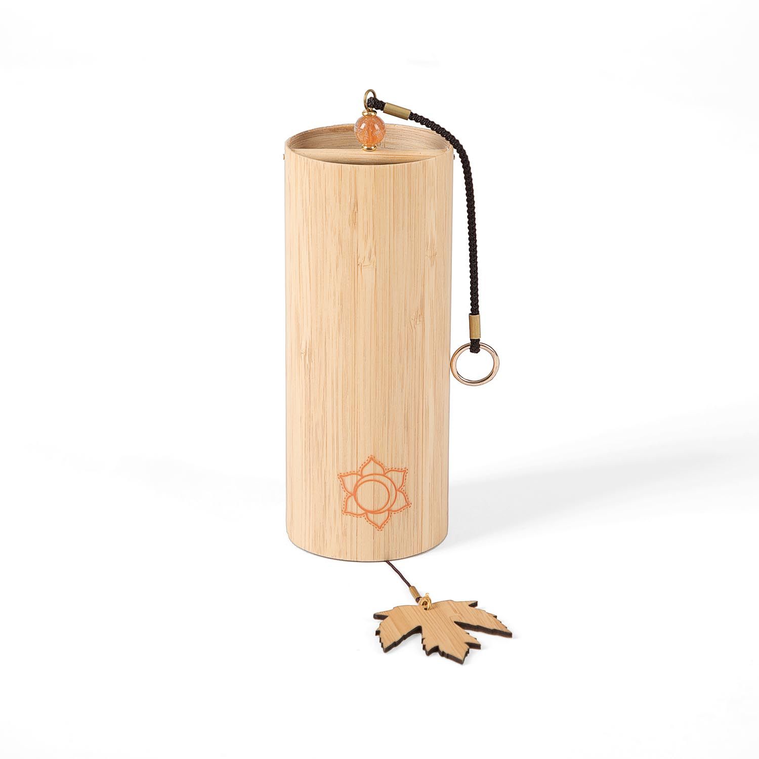 Klangspiel aus Bambus. Zylindrische Form, orangefarbenes Chakra-Symbol. Holzblatt als Anhänger. Schwarze Schnur.
