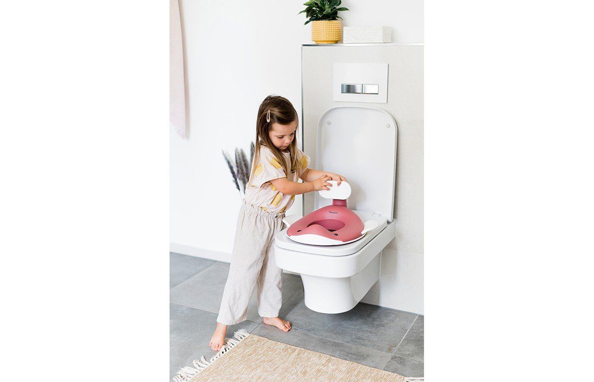 Kind steht vor Toilette mit Toilettensitz in Walform. Kind berührt den Sitz. Badezimmerhintergrund.