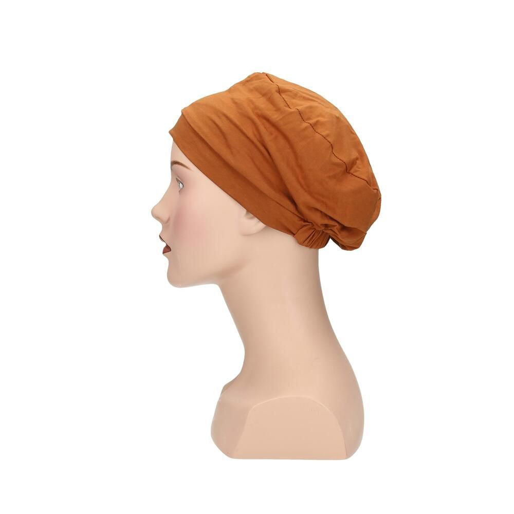 Ockerfarbener Turban auf einer Schaufensterpuppe. Seitenansicht. Stoff mit Falten. Keine weiteren Details.