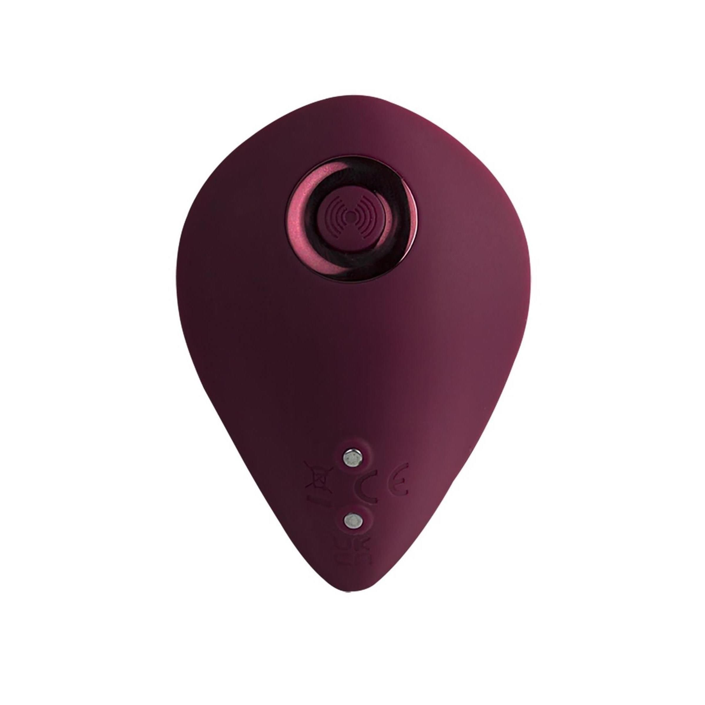 Dunkelrotes, ei-förmiges Produkt. Oberseite mit erhabenen Punkten. Unterseite mit Knöpfen und CE-Zeichen.