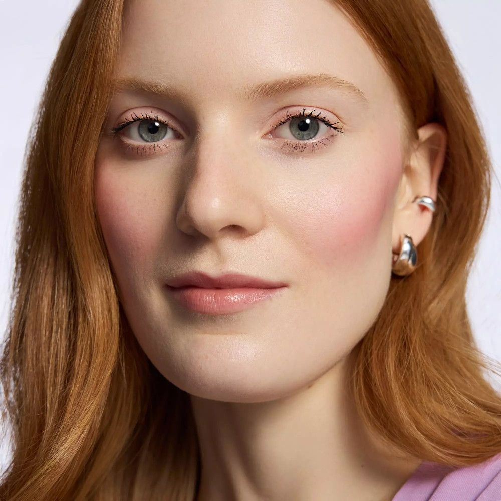 Porträt einer Frau mit Lippenstift. Sie trägt Ohrringe. Natürliches Make-up.