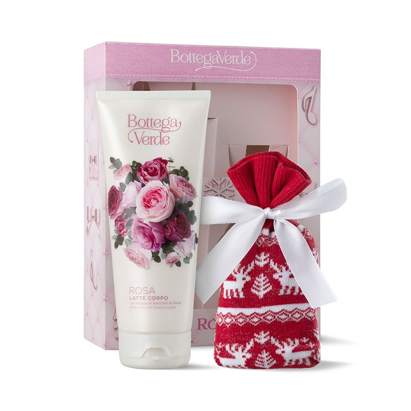 Un cofanetto regalo natalizio Bottega Verde a tema rosa. Contiene un tubetto di lozione per il corpo con un motivo floreale di rose e un piccolo sacchetto rosso con un motivo di renne bianche, legato con un fiocco bianco. La confezione è rosa e riporta il nome del marchio.