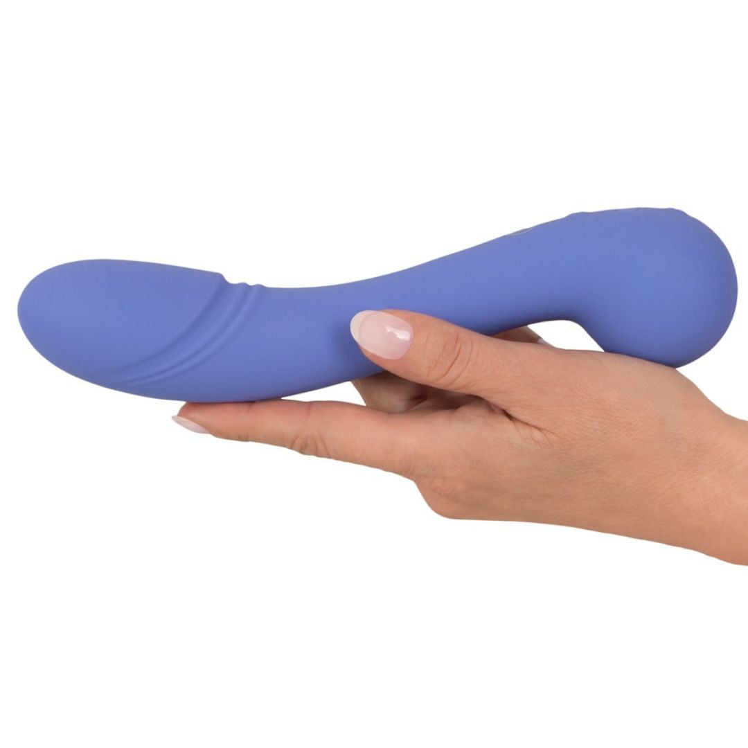 Blau-violetter Vibrator, gehalten in einer Hand. Geschwungene Form. Glatte Oberfläche.