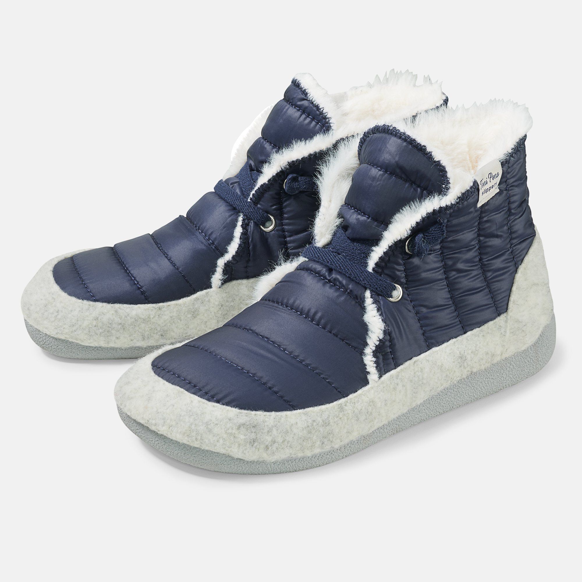 Blaue Pantoletten/Hausschuhe mit weißem Fellfutter. Steppdesign, Schnürsenkel. Graue Sohle. Label am Schaft.