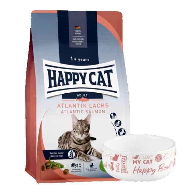 Verpackung von Happy Cat Adult Atlantik Lachs Katzenfutter und Futternapf. Aufschrift: Happy Cat, Atlantik Lachs, 1+ Jahre. Napf mit Aufschrift.