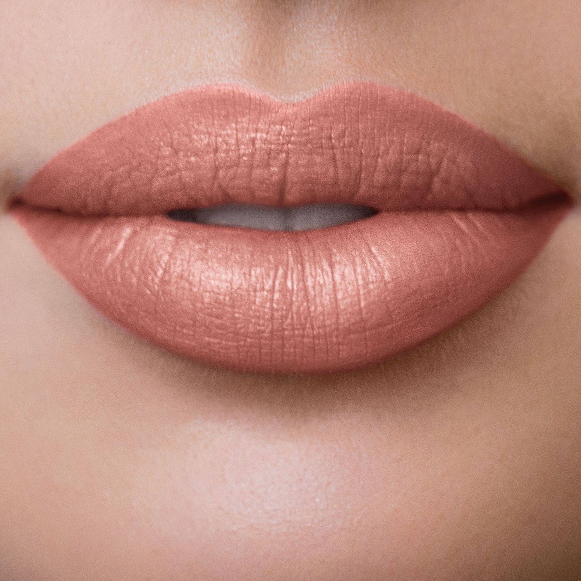 Nahaufnahme von Lippen, die mit rosafarbenem Lippenstift geschminkt sind. Die Lippen sind leicht glänzend.