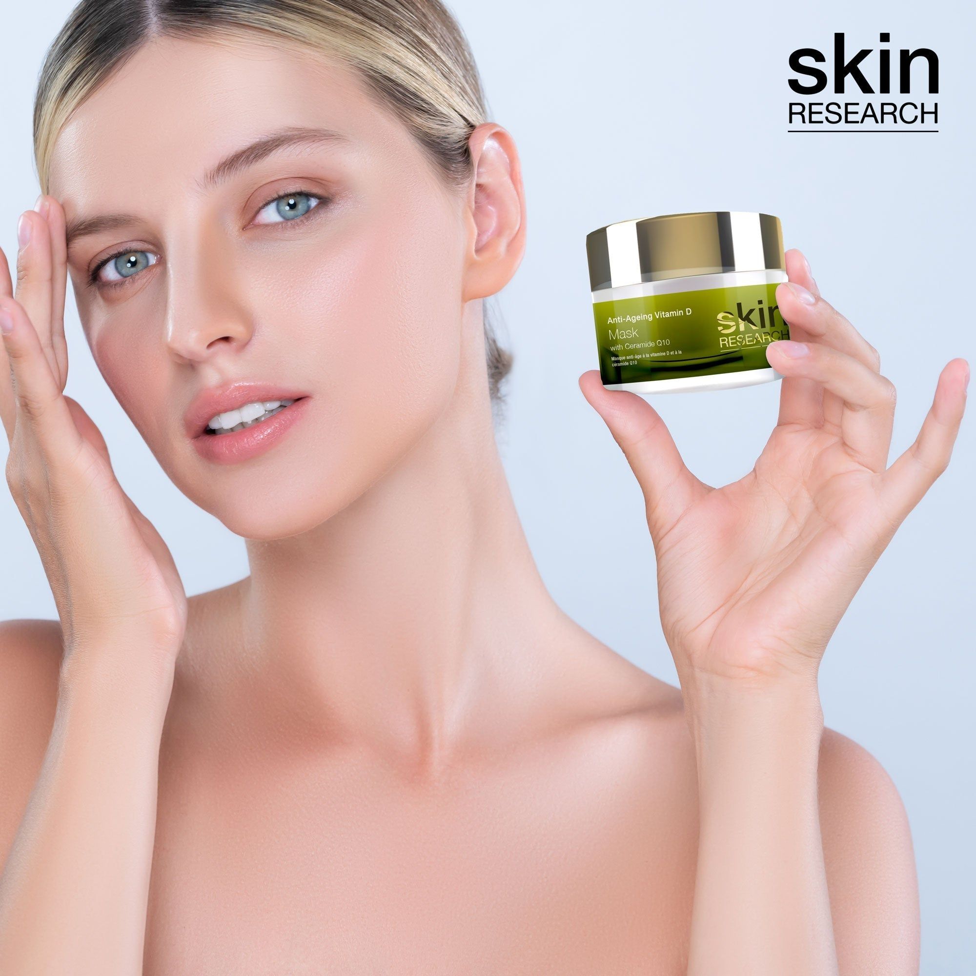 Frau hält eine Creme-Dose. Auf der Dose steht "Anti-Ageing Vitamin D Maske" und "Skin Research".