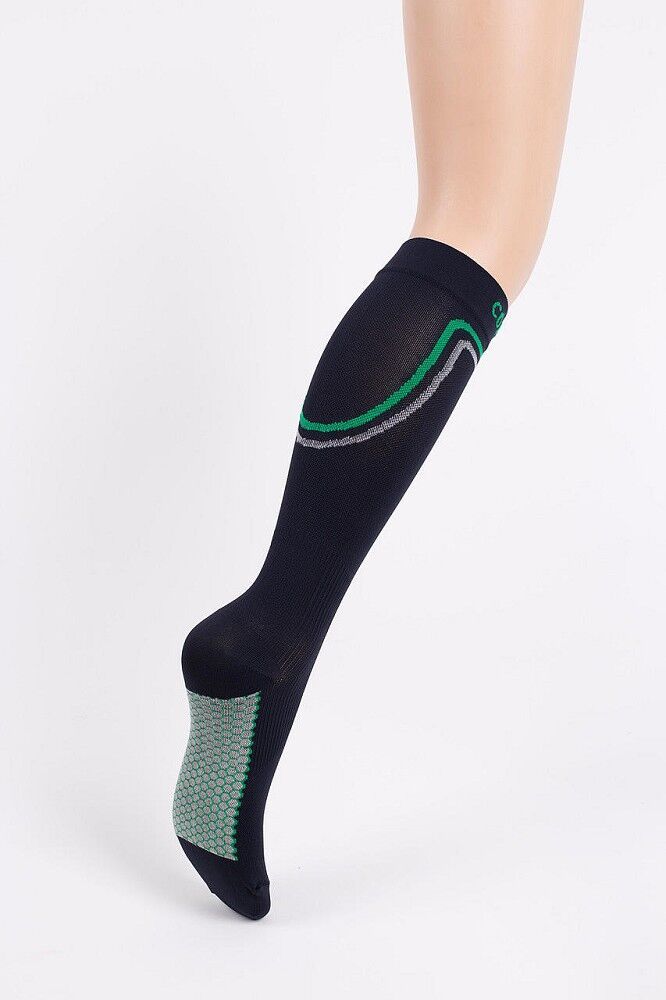 Dunkelblaue Kniestrümpfe mit grün-grauen Akzenten. Grün-graues Muster an der Sohe. Kompressionsstrümpfe am Bein einer Person.