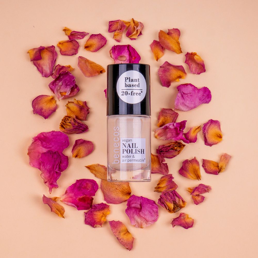 Benecos Nagellackflasche umgeben von getrockneten Rosenblättern.
