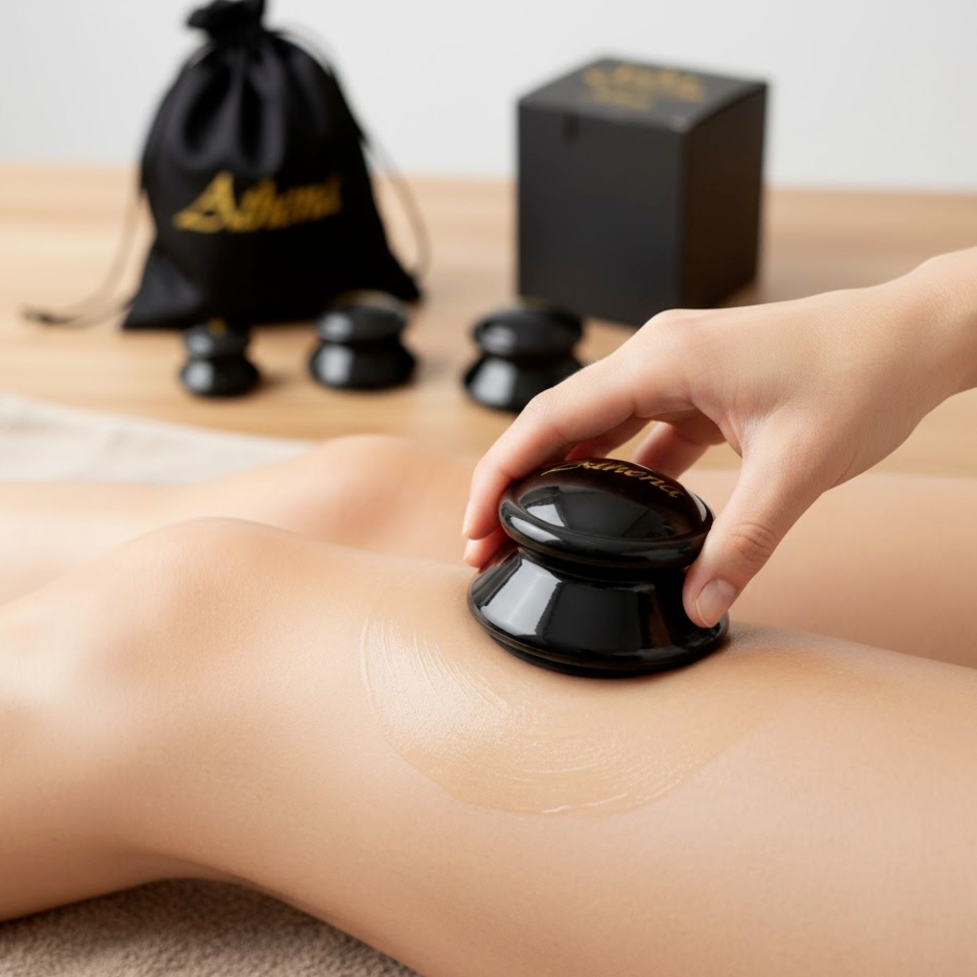 Hand hält einen schwarzen Schröpfbecher auf einem Bein. Auf dem Bein ist eine Flüssigkeit sichtbar.