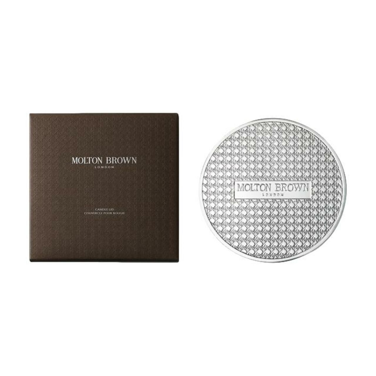 Braune Schachtel und silberner Deckel. Auf der Schachtel steht "Molton Brown London". Der Deckel ist rund und hat ein Muster.