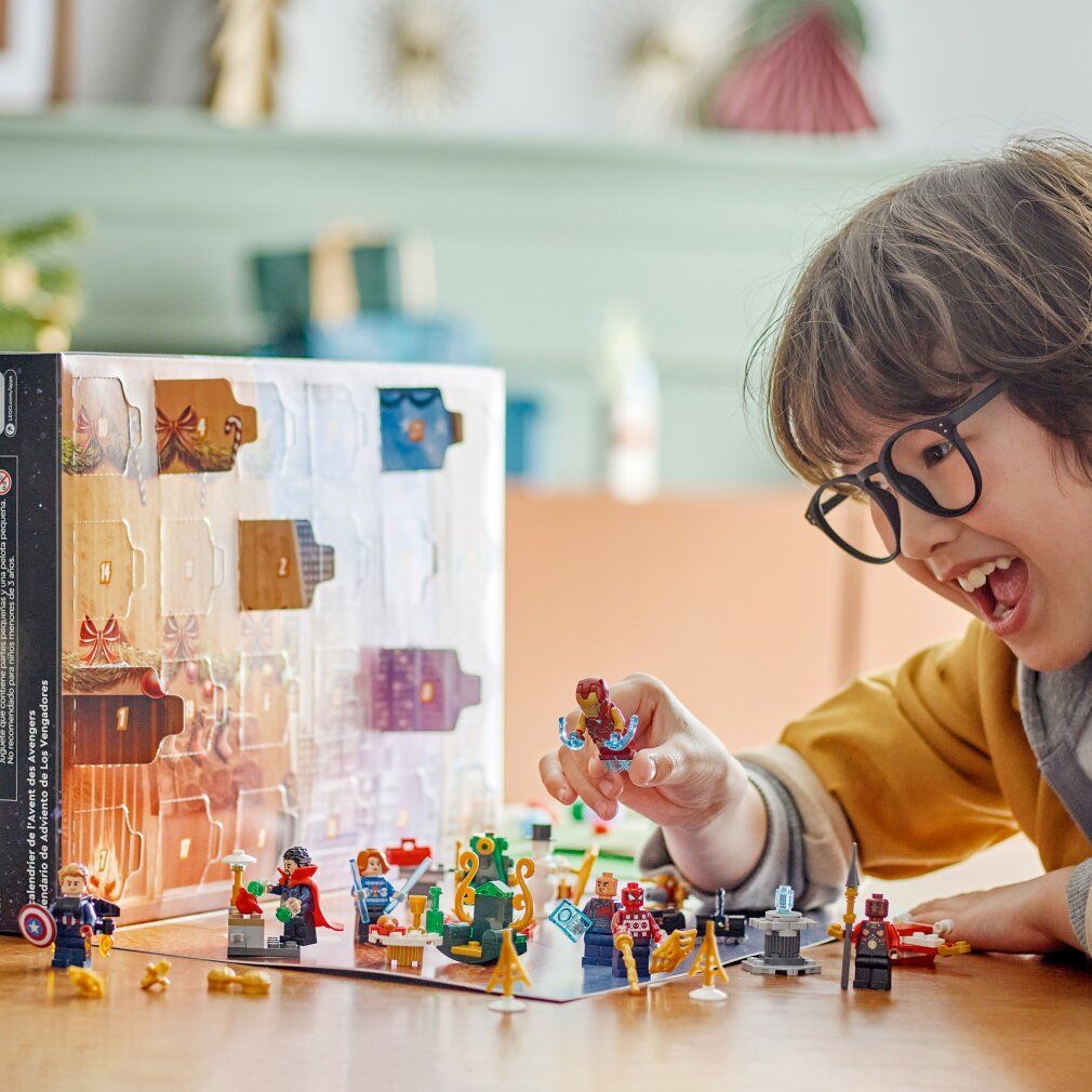 Kind spielt mit LEGO Marvel Adventskalender. Figuren und Szenen auf Tisch. Enthält Iron Man, Spider-Man und Captain America.
