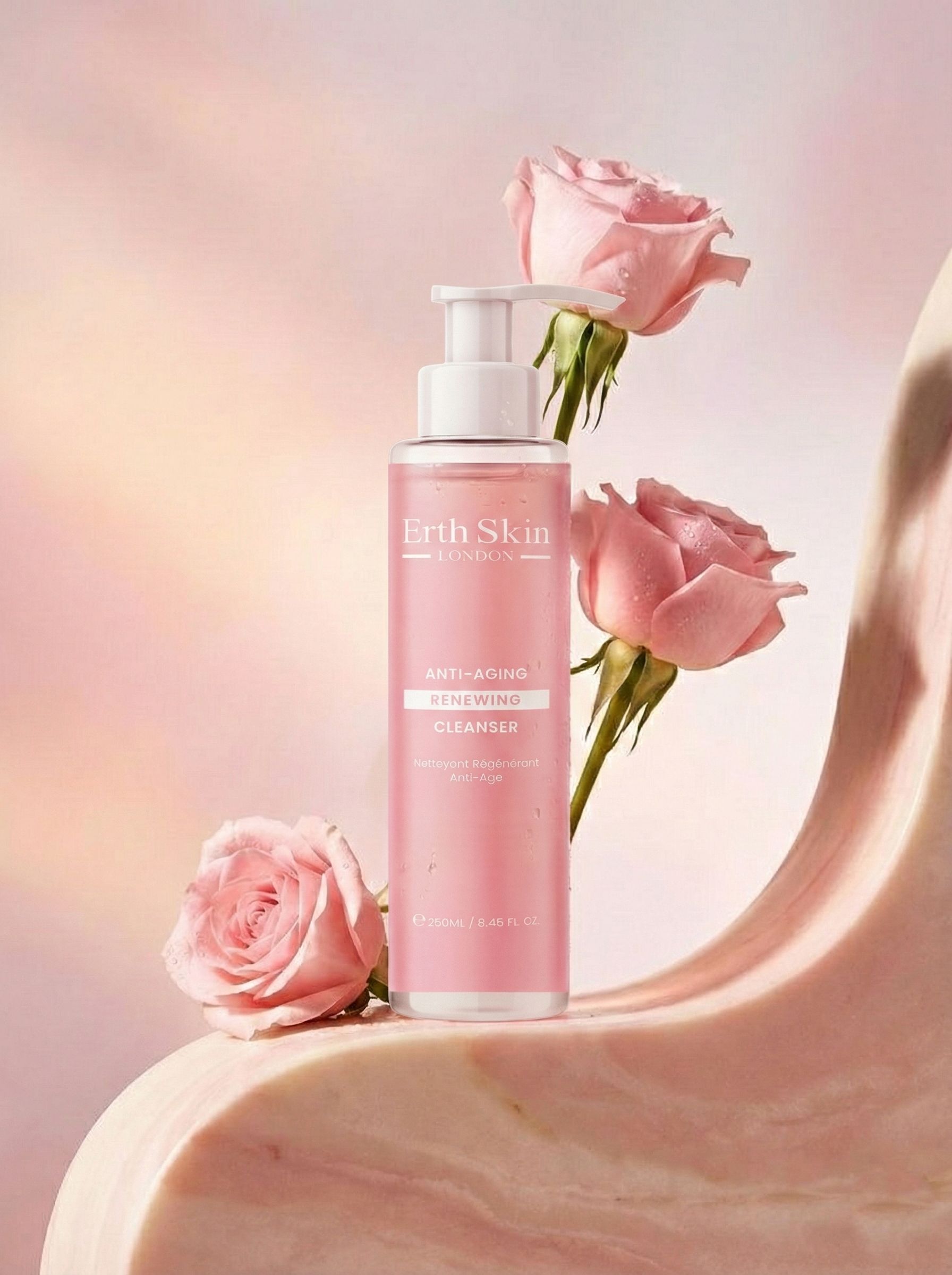 Rosa Flasche mit Pumpe, umgeben von Rosen. Aufschrift: Erth Skin London, Anti-Aging Renewing Cleanser. Rosa Hintergrund.
