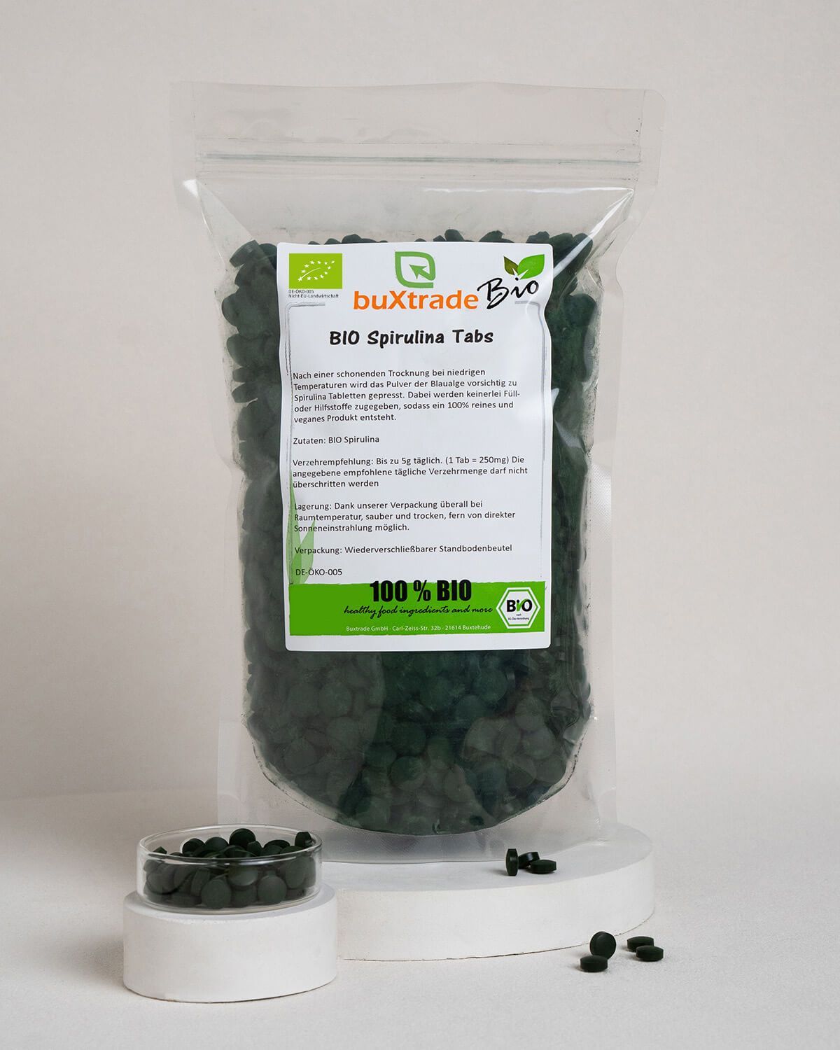 Buxtrade Bio Spirulina Tabs, ein kleiner Behälter mit Tabletten, einige Tabletten verstreut.